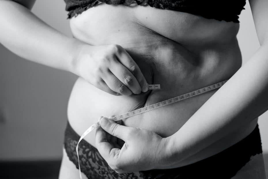 A picture of a tape measure around a women's wait with pinchable fat tissue.